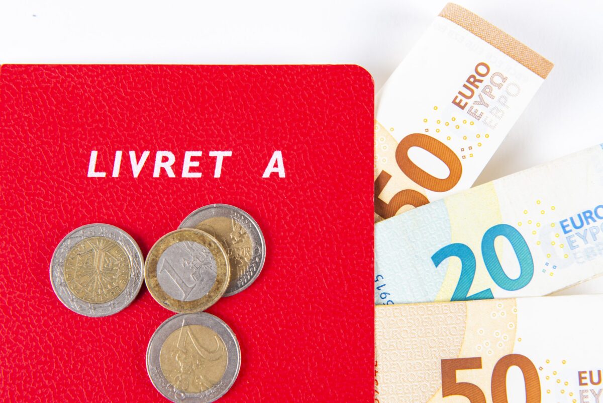 Un Livret A rouge avec des billets et des pièces en euros.